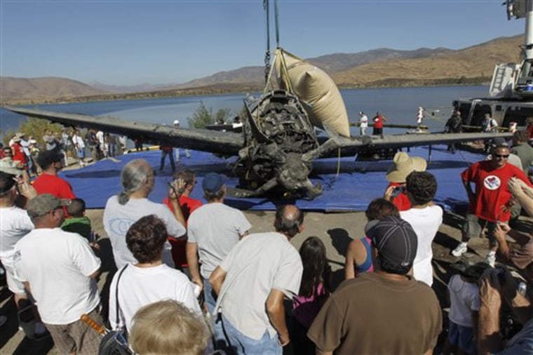 Folks gather around a SB2C Helldiver after it was recovered from 91 feet down and under six or seven feet of organic silt in a San Diego reservoir, Friday, Aug. 20, 2010. Salvage divers, working with the National Naval Aviation Museum, removed the a rare World War II dive bomber that crashed after its engine failed during a training exercise on May 28, 1945. (AP Photo/Chris Carlson)